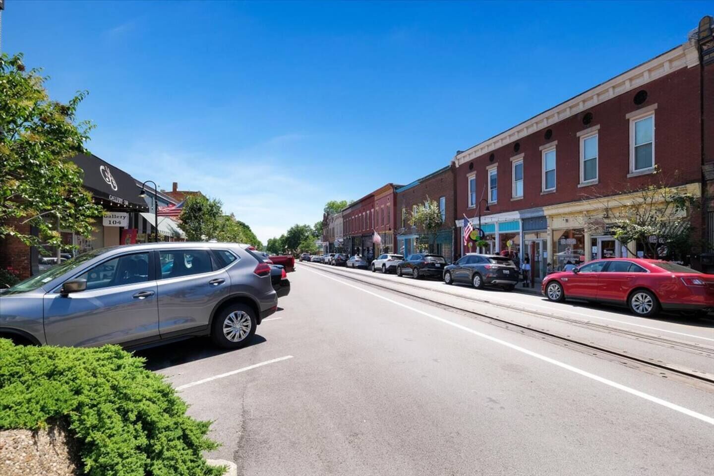 A street with parked cars and buildings on both sides.