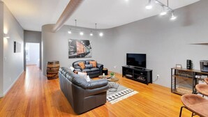 Un salon moderne avec un canapé en cuir, un téléviseur à écran plat et un plancher en bois.