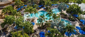 A resort with multiple swimming pools surrounded by palm trees and blue umbrellas. - Resort Living at its Finest in Fort Myers! (Fort Myers)