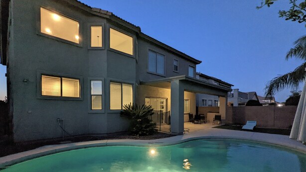 Una casa de dos pisos con una piscina al frente.