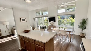 Una cocina moderna con una isla grande, armarios de madera y un comedor con mesa y sillas.