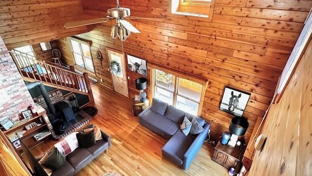 Una cabaña amplia con interior de madera, chimenea, sofá y zona de comedor.