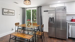 A modern kitchen with a stainless steel refrigerator, a dining table with chairs, and a window with curtains. - NEW! 19 Minutes from Savannah Historic District (Bloomingdale)