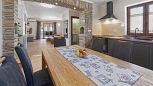 Une cuisine moderne avec une arche en pierre, un coin repas avec une table dressée pour deux personnes, et une vue sur le salon.