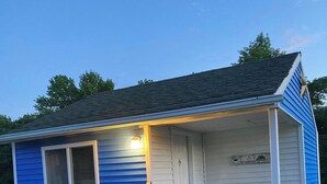 A small house with a porch, a window, and a door. - The Blue Cottage@ Twin Hills Cottages (Ellsworth)