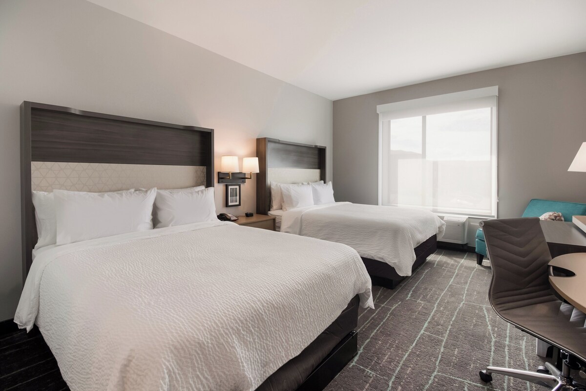 Une chambre d’hôtel avec deux lits, un bureau et une chaise.