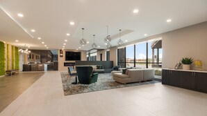 A spacious living area with a sofa, chairs, a coffee table, and a kitchen in the background.