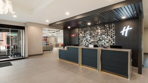 A modern reception area with a dark reception desk, a logo, and a wall of sunglasses.