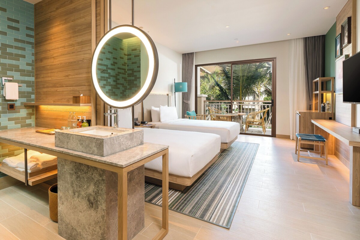 Una moderna camera d'hotel con bagno in marmo, un ampio letto, una scrivania e un balcone con vista sull'esterno.