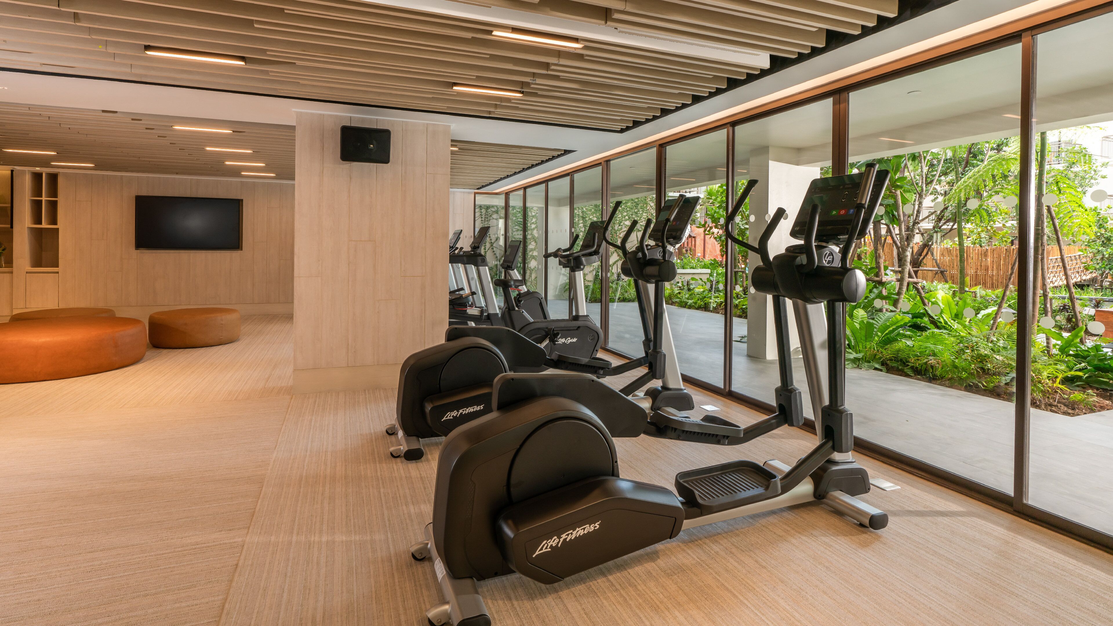 Un gimnasio con cintas de correr, elípticas y una pantalla de televisión.
