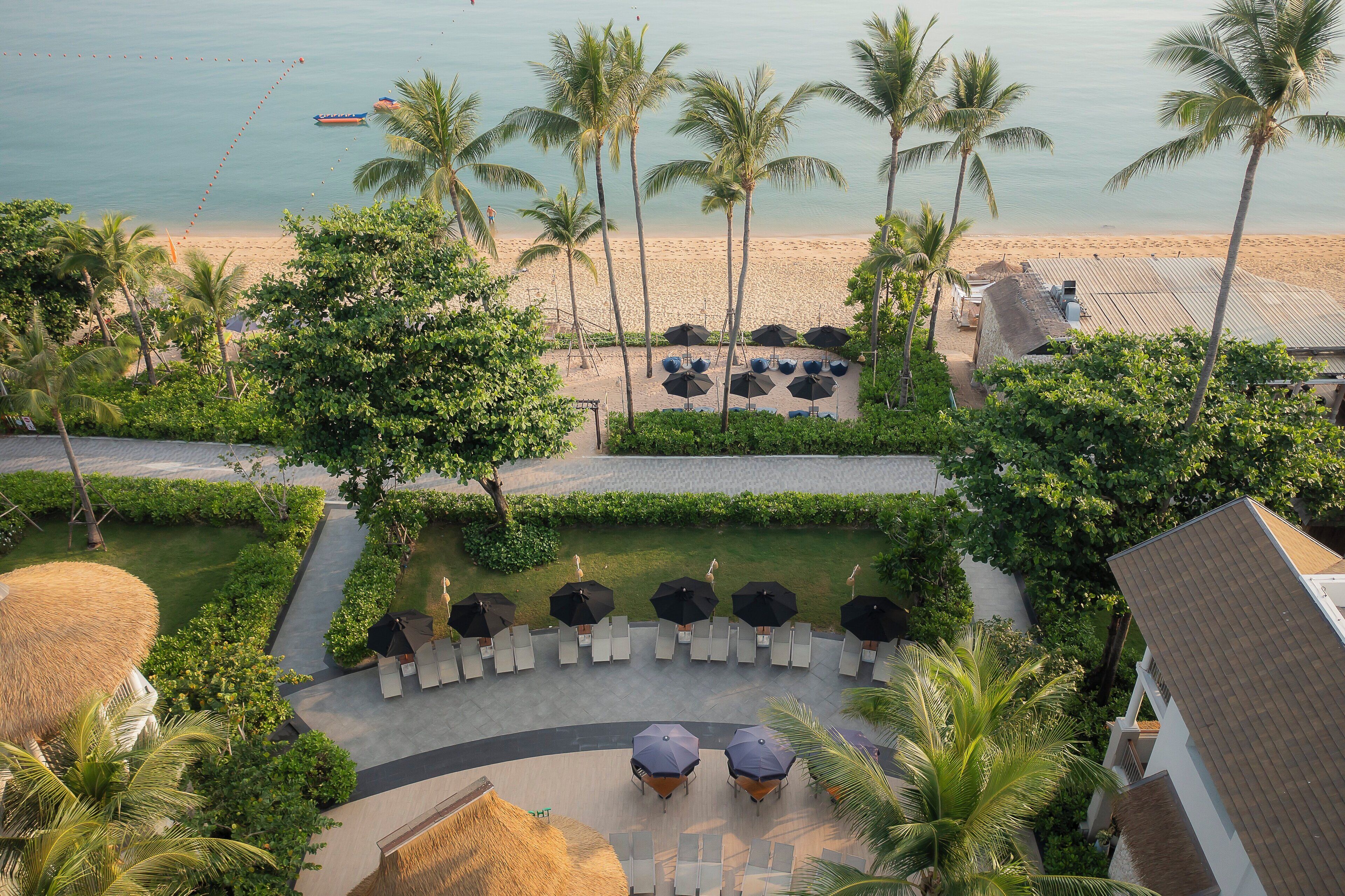 Ein Resort mit Blick auf den Strand, Palmen und Sitzbereichen im Freien.