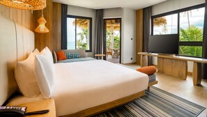 A modern hotel room with a large bed, a TV, and a balcony with a view of palm trees. - Holiday Inn Resort Samui Bophut Beach by IHG (Koh Samui)