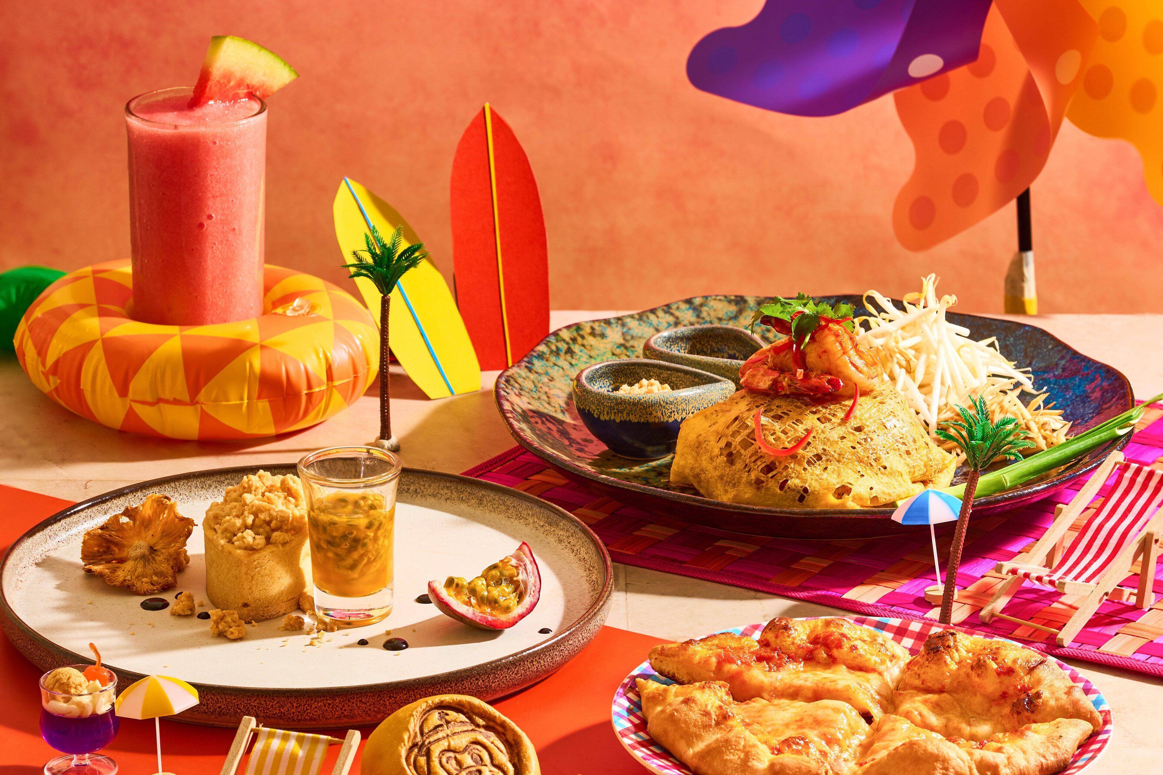 Una mesa con diferentes platos, bebidas y una tabla de surf.