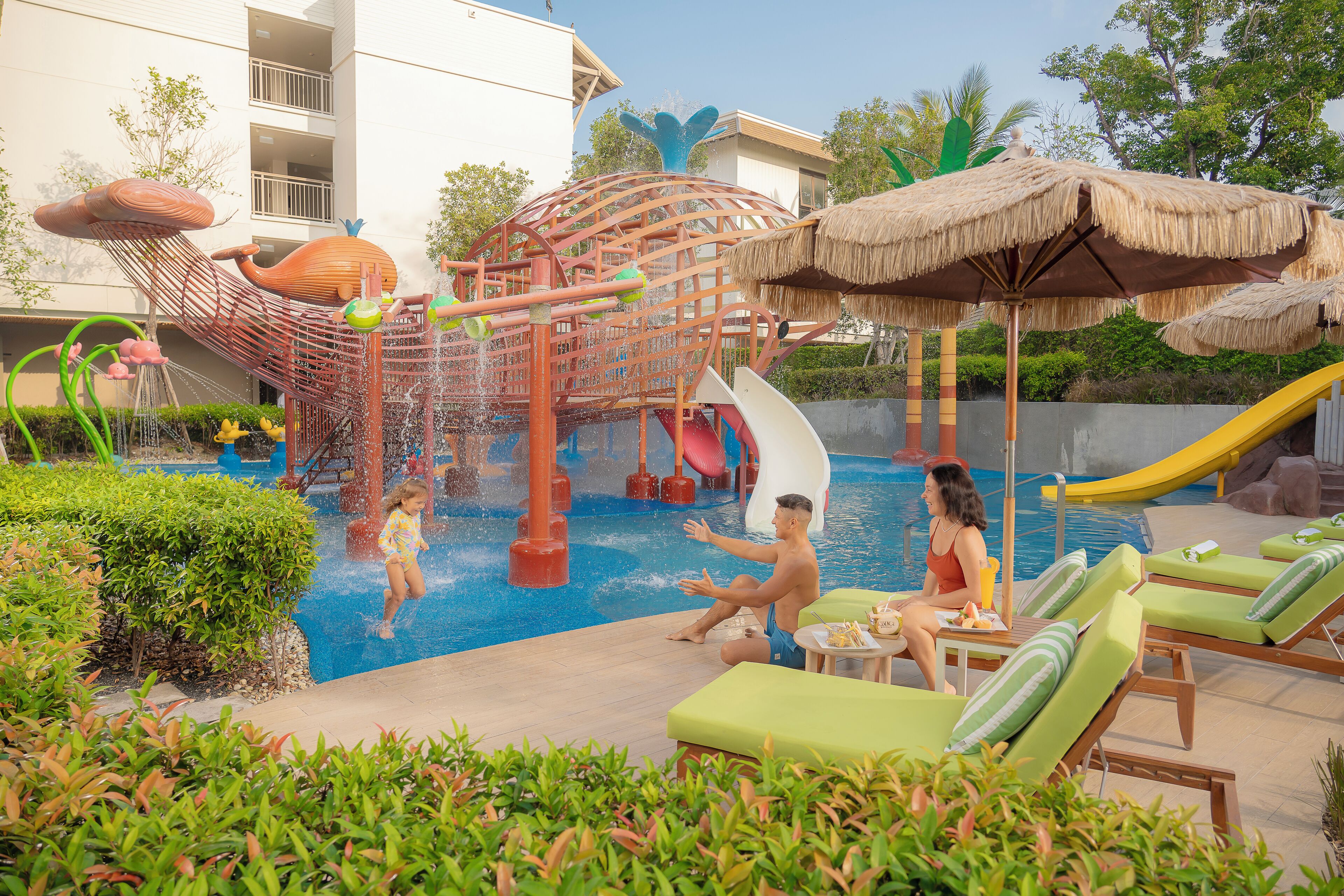 A water park area with slides, a play structure, and lounge chairs by the pool.