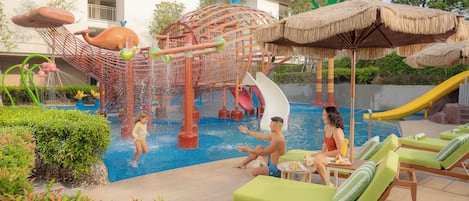 A water park area with slides, a play structure, and lounge chairs by the pool.