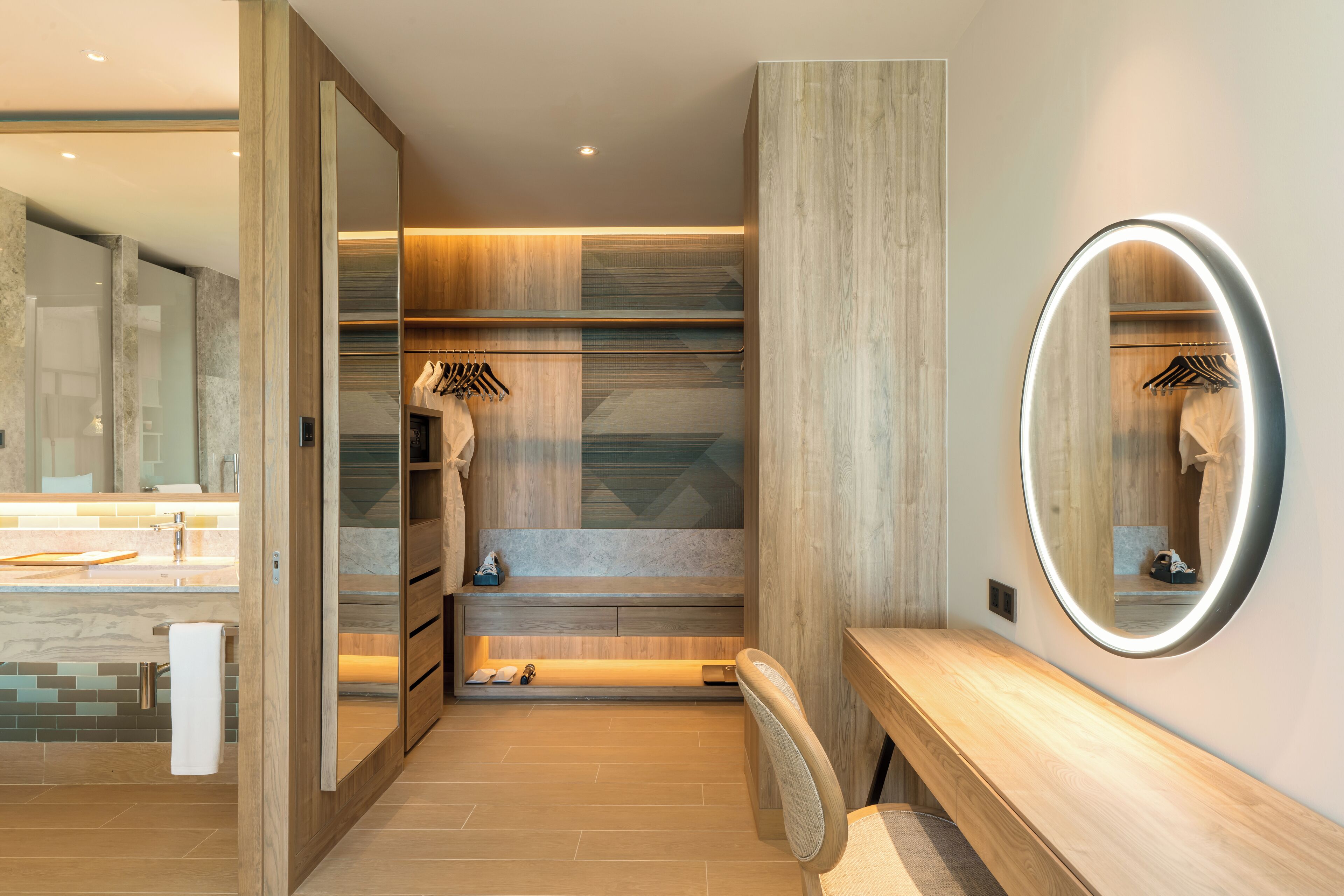 A modern bathroom with a wooden vanity, a large mirror, and a bench.