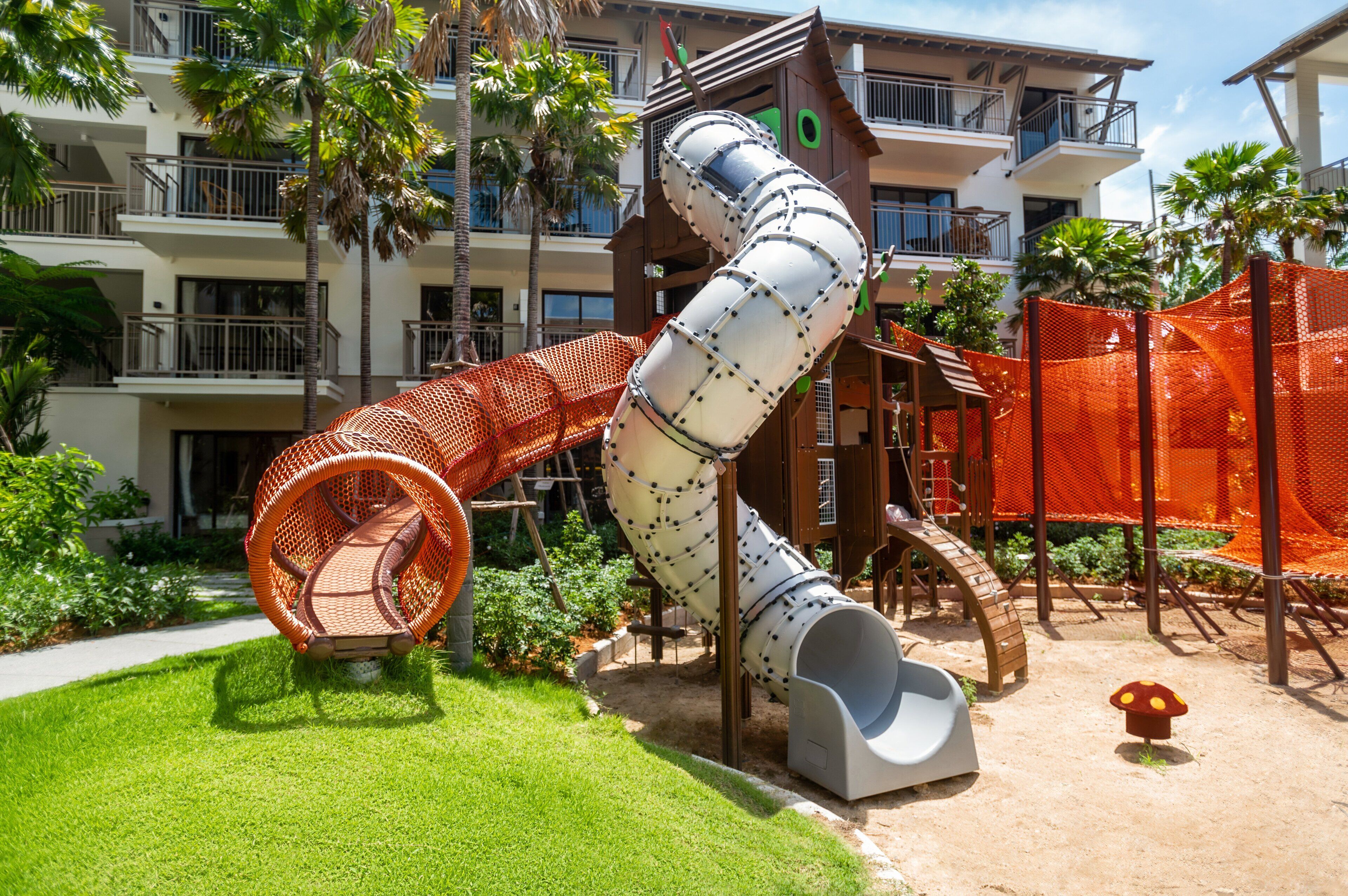 A playground with a slide, swings, and a playhouse.