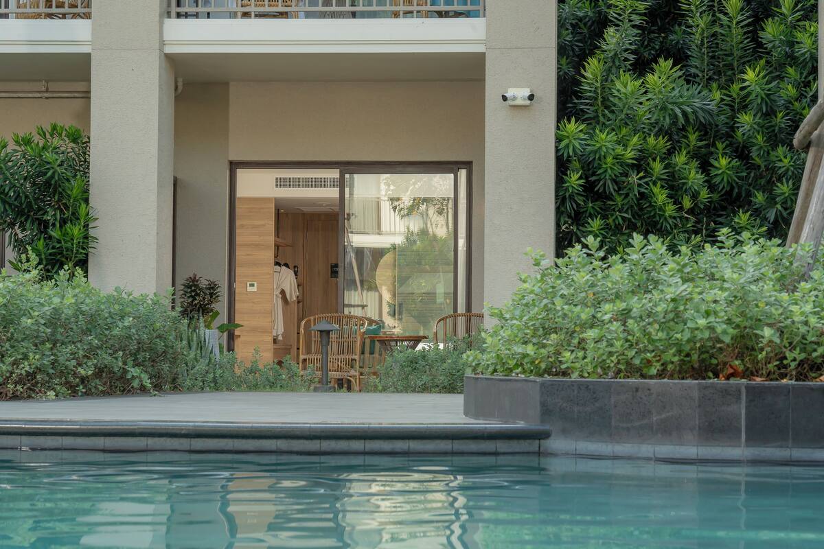 A pool area with a clear view of the pool, a wooden deck, and a seating area with chairs and a table.