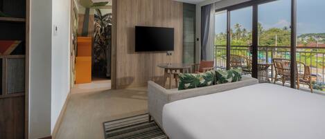 A modern hotel room with a large bed, a flat-screen TV, a small table, and a balcony with a view of the landscape.