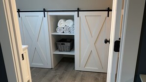 A walk-in closet with sliding doors, a wooden floor, and a storage basket.