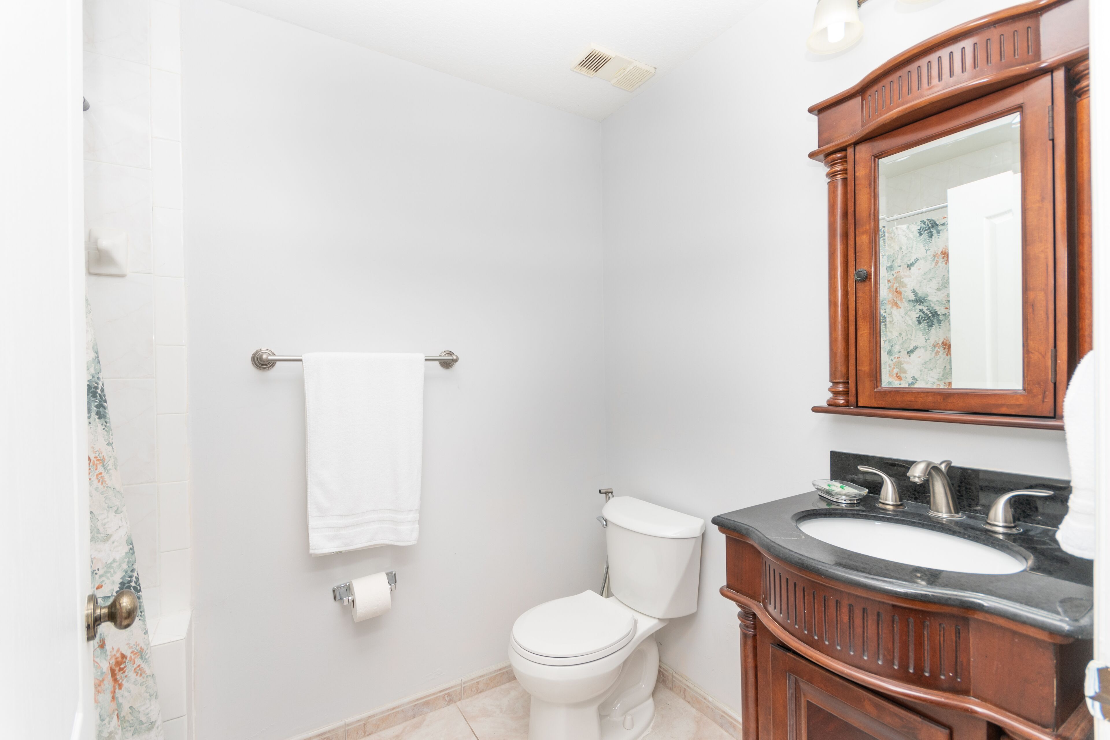 A bathroom with a toilet, sink, and mirror.