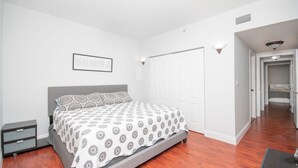 A bedroom with a bed, a nightstand, a wardrobe, and a hallway leading to another room. - Beautiful 2/2.5 Condo w/Free Parking Fast WIFI (Miami)