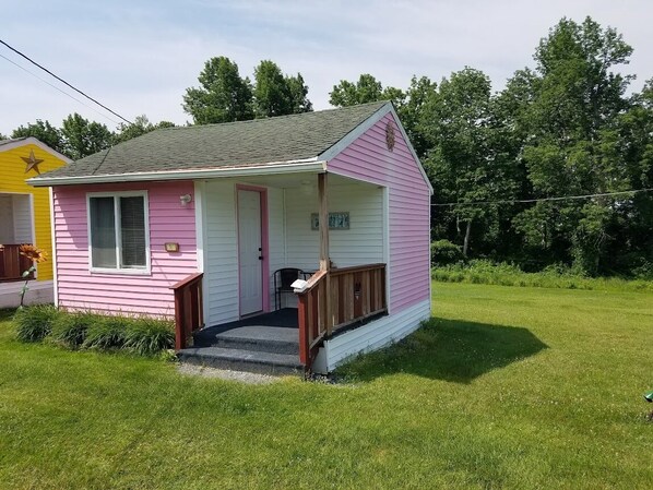 Une petite maison rose et blanche, dot ée d’un porche et d’une seule porte.