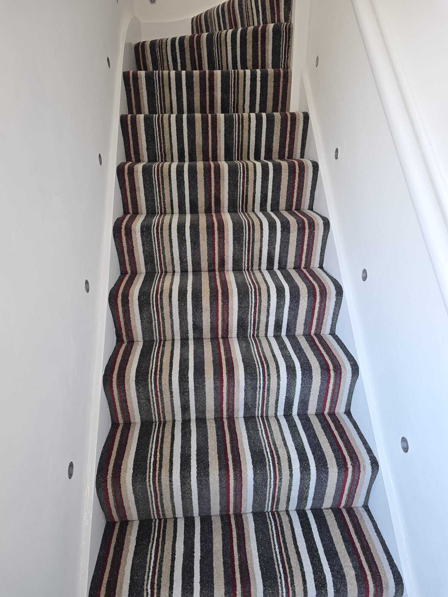 Eine Treppe mit Streifenmuster-Teppich und weißen Wänden.