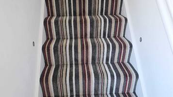 A staircase with striped carpet and white walls.