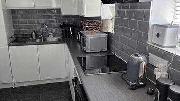A modern kitchen with white cabinets, a black countertop, and a stainless steel sink.