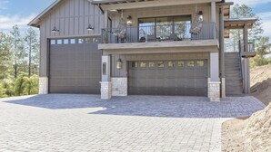 Ein zweistöckiges Haus mit großer Garage, einem Balkon mit hängenden Lichtern und einem Steinfundament.
