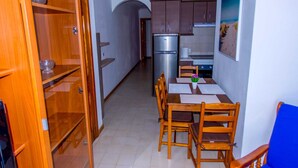 A compact kitchen with wooden cabinets, a stainless steel refrigerator, and a dining area with a table and chairs. - Suitable. Deep beach, a few meters from the beach. (Playa Honda)
