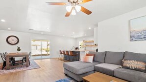 A modern living room with a grey sectional sofa, a wooden coffee table, and a ceiling fan. - Stunning Gilbert Home w/ Heated Pool and Hot Tub (Mesa)