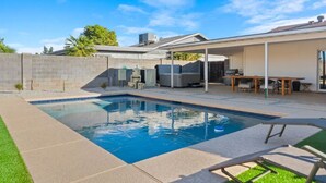 A backyard with a swimming pool, a covered patio area, and a brick wall. - Stunning Gilbert Home w/ Heated Pool and Hot Tub (Mesa)