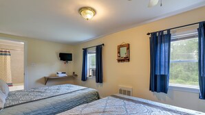 Ein Schlafzimmer mit zwei Betten, einem Fernseher, einem Fenster mit Vorhängen und einem Spiegel an der Wand.