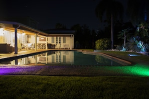 Uma casa com piscina, área de estar externa e um pátio coberto.