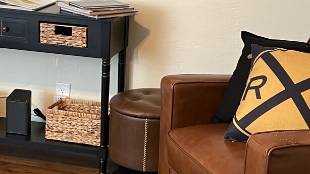 Un salon avec un canapé en cuir marron, un meuble de rangement noir et un téléviseur à écran plat fixé au mur.