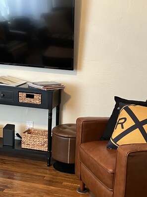 Un salon avec un canapé en cuir marron, un meuble de rangement noir et un téléviseur à écran plat fixé au mur.