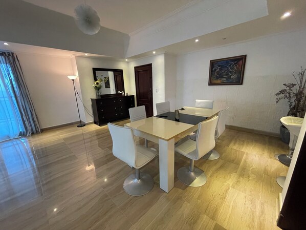 A modern dining area with a rectangular table, six chairs, and a dark wooden cabinet.