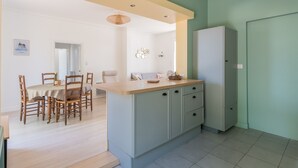 Una cucina moderna con isola centrale, mobili chiari e zona pranzo con sedie e tavolo in legno.