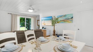 A dining area with a table set for four, white chairs, and a ceiling fan. - Townhome with Gulf Access (Miramar Beach)