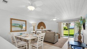 A dining area with a white table set for four, a sofa, and a ceiling fan. - Townhome with Gulf Access (Miramar Beach)