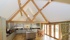 A spacious kitchen with a central island, wooden beams, and a large window with curtains. - Rookery Hall (Broadway)