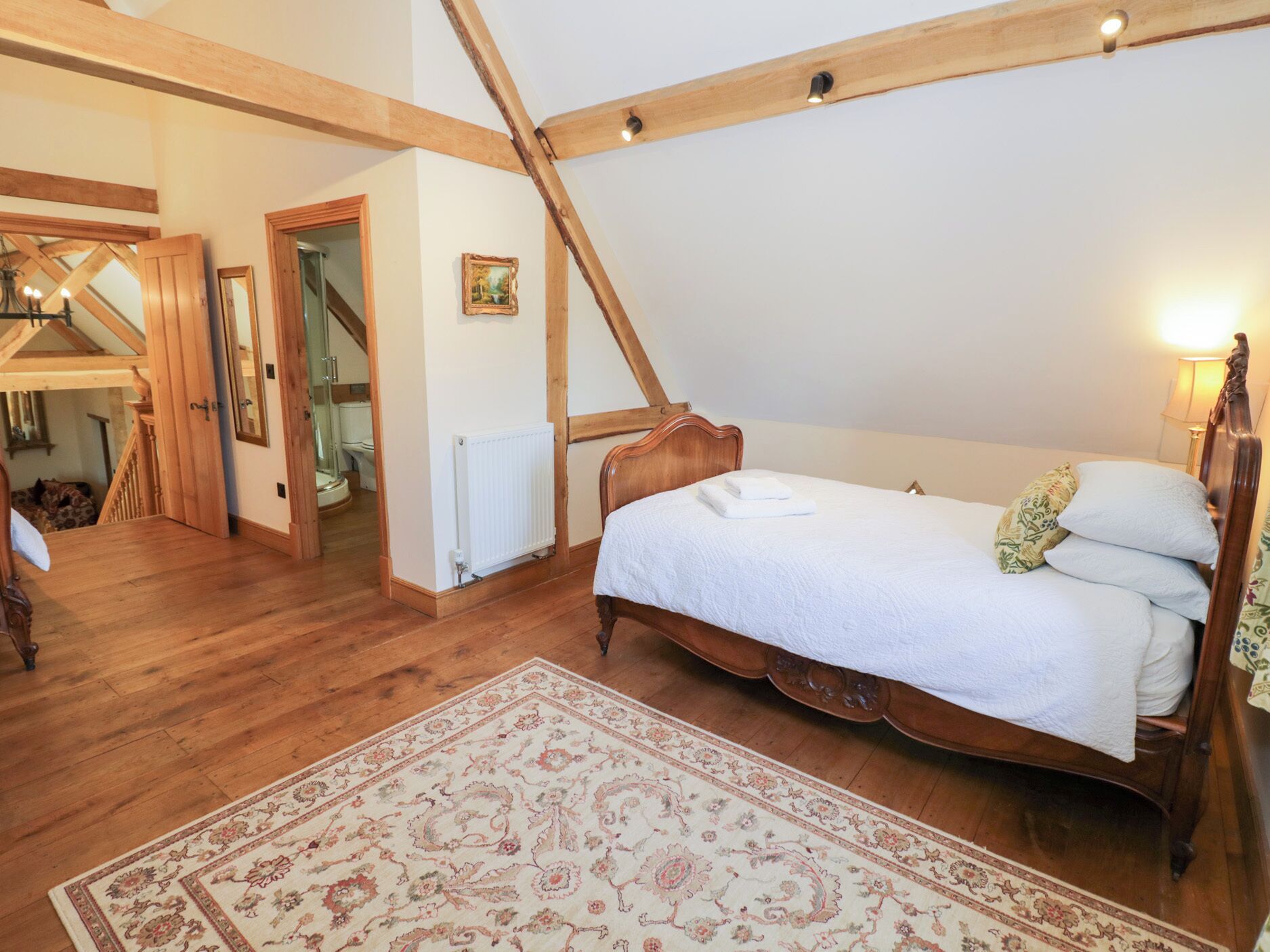 Un dormitorio con una cama de madera, un tapete grande y una escalera que lleva a un nivel superior.