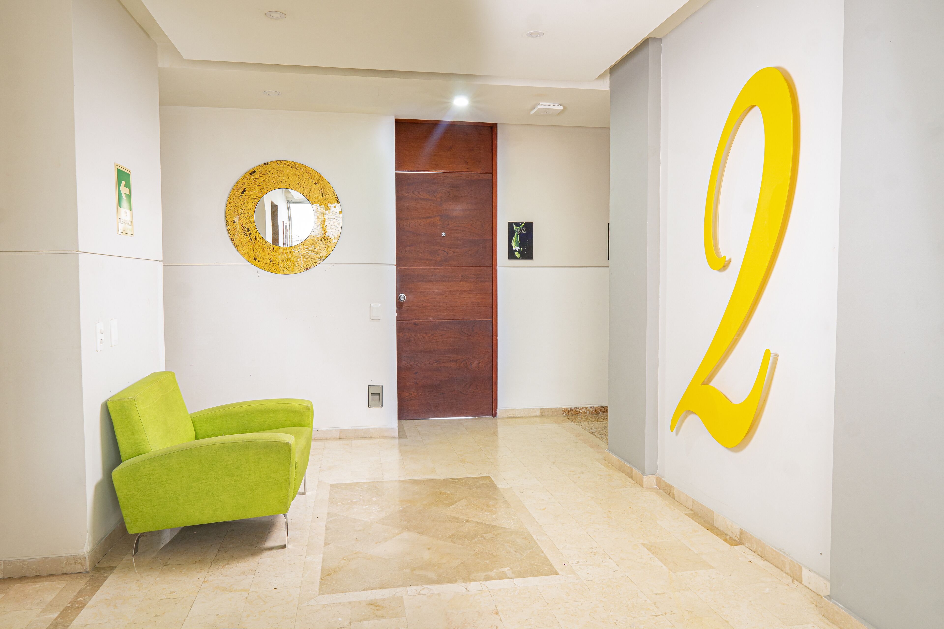 A hallway with a green chair, a wooden door, and a large yellow number '2' on the wall.