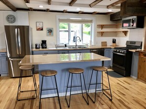 Una cocina moderna con una isla central, electrodomésticos de acero inoxidable y taburetes de madera.
