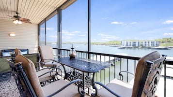 A balcony with a table and chairs, overlooking a body of water and buildings.