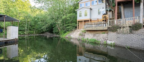Overlooking the serene lake, this two-story house offers a tranquil retreat with a spacious balcony and a wooden deck extending into the water.