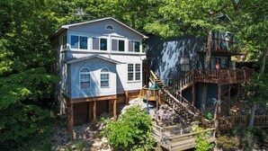 Une maison à deux étages dotée d’une terrasse en bois et d’un escalier menant à un balcon.