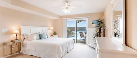 Un dormitorio con cama, lámparas de noche, ventilador de techo, balcón con vistas y cómoda.